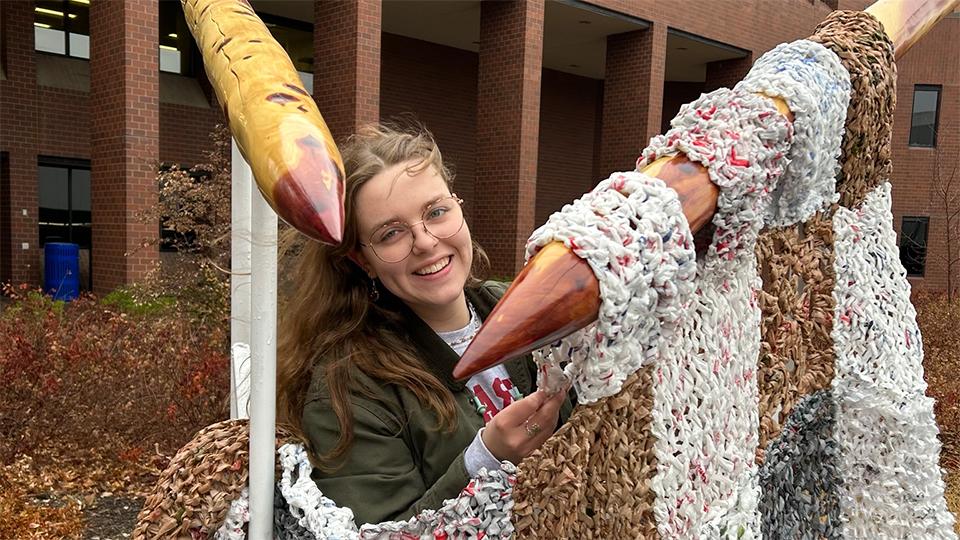 Alayna Reinke posing with her sustainability sculpture